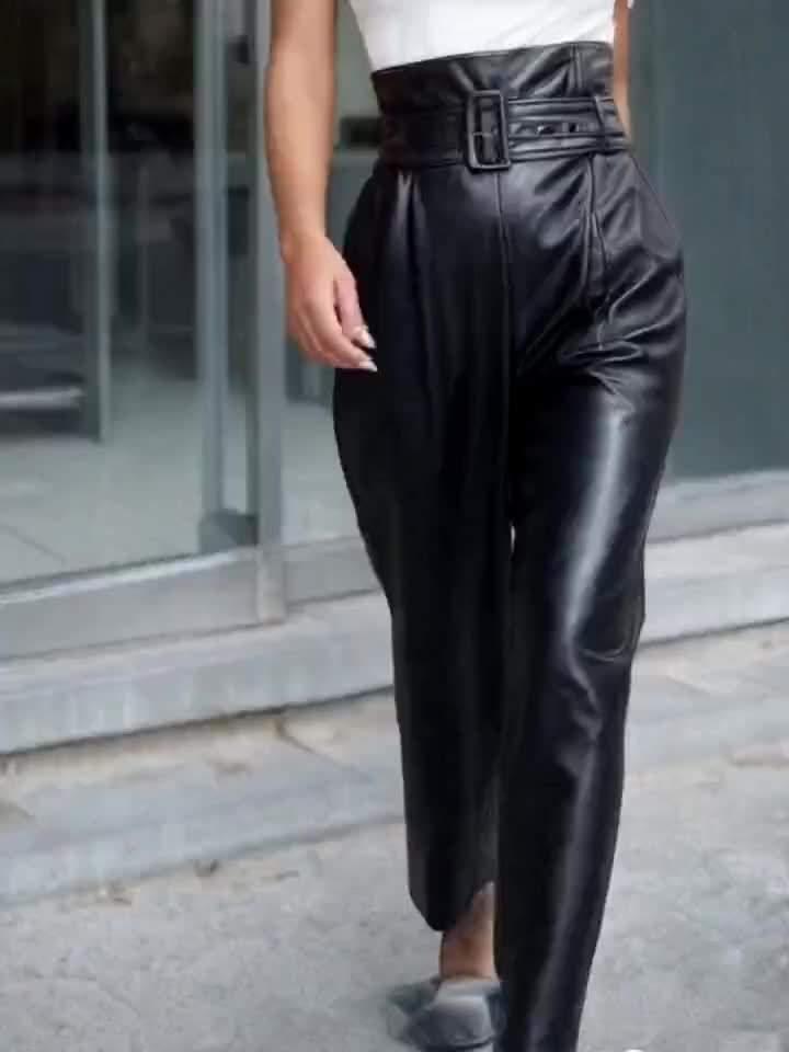 Calça de couro sintético, com cinto e detalhe de zíper